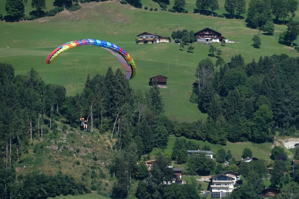 Gleitschirm im Flug über grüner Hügelregion