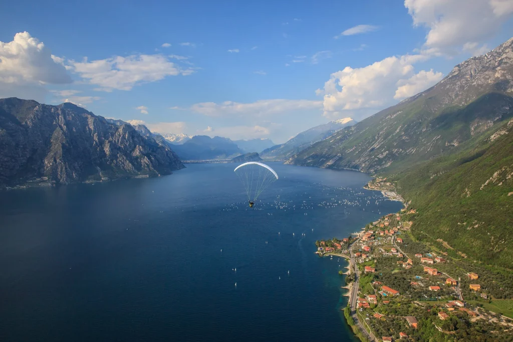 Blick auf den Gardasee mit Gleitschirm und Dorf am Ufer