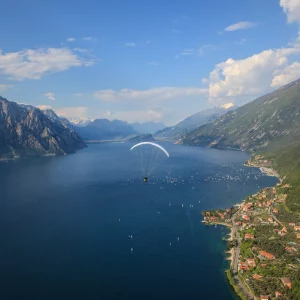 Blick auf den Gardasee mit Gleitschirm und Dorf am Ufer